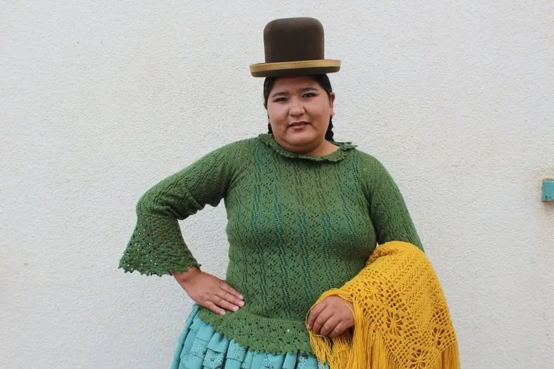 Mujer con sombrero y chompa verde posando de pie